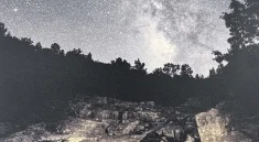 A night sky filled with stars above a rocky landscape