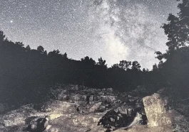 A night sky filled with stars above a rocky landscape