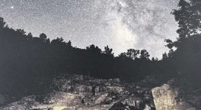 A night sky filled with stars above a rocky landscape