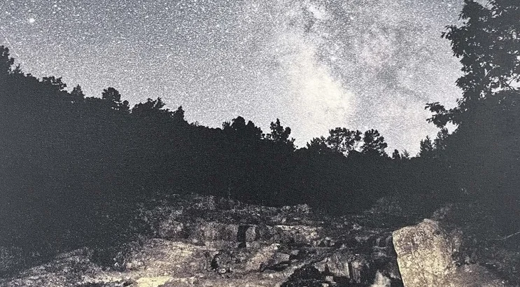 A night sky filled with stars above a rocky landscape
