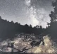 A night sky filled with stars above a rocky landscape