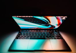 Close-up of an illuminated laptop keyboard and screen in a dark setting