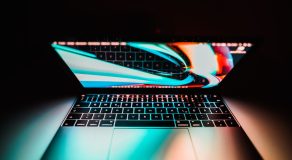Close-up of an illuminated laptop keyboard and screen in a dark setting